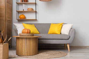 Gri kanepe, masa ve balkabaklarıyla oturma odasının içinde.