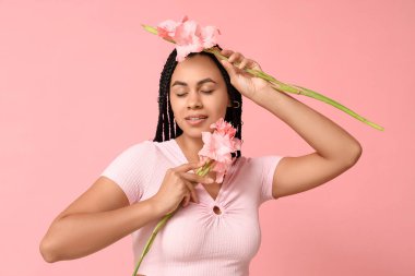 Pembe arka planda gladyatör çiçekleri olan güzel bir Afro-Amerikalı kadın.