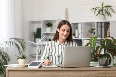 Ofiste çalışan rüzgar türbini modelli kadın mühendis.