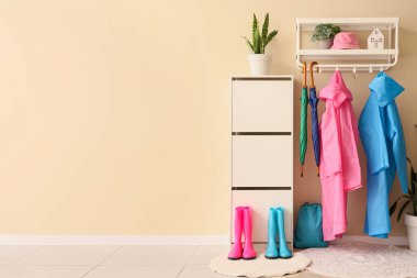 Koridorun içinde yağmurluklar, çizmeler ve çekmeceler var.