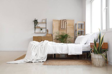 Büyük yatak, raf ünitesi, katlanan ekran, yatak odasının iç tarafındaki saksı ve çekmeceler.