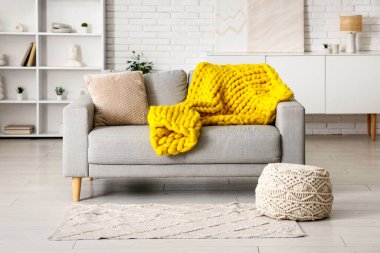 Modern oturma odası, şık gri kanepe, puf ve sarı ekose örgü.