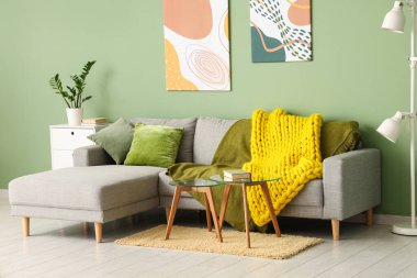 Modern oturma odası, şık bir kanepe, masalar ve sarı örülü ekose kumaş.