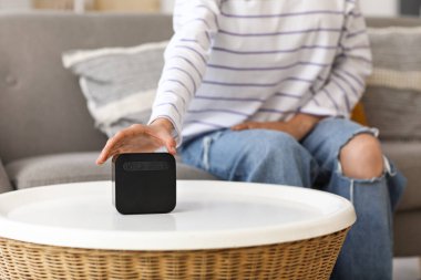 Evdeki masadaki kablosuz hoparlörlü güzel genç kadın, yakın plan.