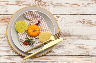Altın çatal bıçak takımı ve hafif ahşap arka planda sonbahar dekoru olan güzel bir masa.