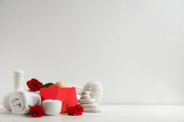 Spa aksesuarlı kompozisyon, kırmızı gül çiçekleri ve açık ahşap masa üzerindeki zarf Sevgililer Günü kutlaması