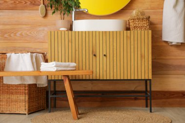 Dolabı, lavabosu ve ahşap tezgahı olan şık bir banyo.