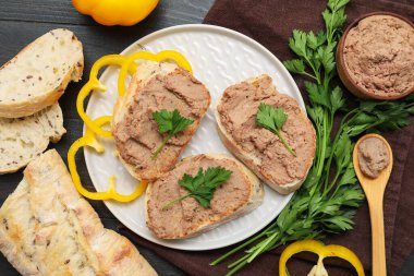 Kızarmış ekmek tabağı, bir kase lezzetli börek, maydanoz ve koyu ahşap arka planda dolma biber dilimleri.