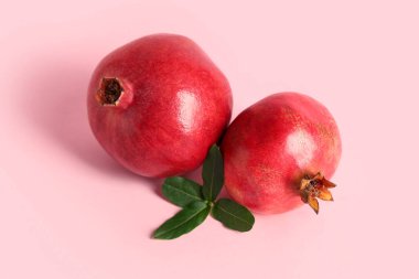 Pembe arka planda taze nar ve yapraklar.