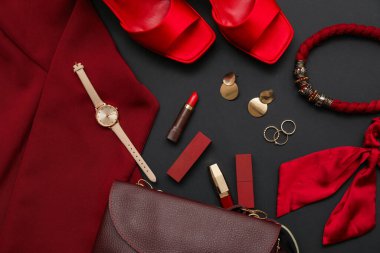 Kozmetik ürünleri, aksesuarlar, kol saati ve yeşil arka planda ruj izi. Yakın çekim.