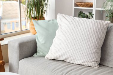 Oturma odasındaki gri koltukta şık yastıklar, yakın plan.