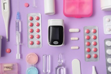 Nabız oksimetresi, steteskop ve eflatun arkaplan üzerindeki ilaçlar, yakın plan.