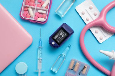 Nabız oksimetresi, steteskop ve mavi arka planda ilaç bileşimi, yakın plan.