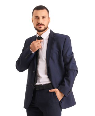Takım elbiseli genç işadamı beyaz arka planda kravatını düzeltiyor.