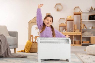 Evinde elektrikli konteyner ısıtıcısı olan mutlu küçük kız.
