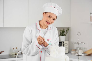 Kadın pastacı mutfakta kremalı kek yapıyor.