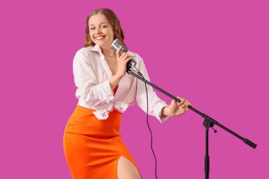 Mikrofonlu güzel genç bir kadın menekşe arkaplanda karaoke söylüyor.