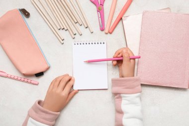 Çocuğun elleri kağıda gri arkaplana bir şeyler yazıyor. Üst görünüm