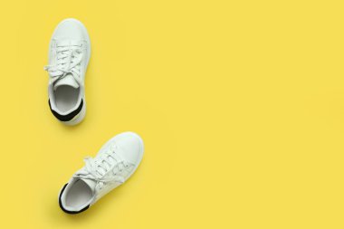 Sarı arka planda beyaz çocuk ayakkabıları.