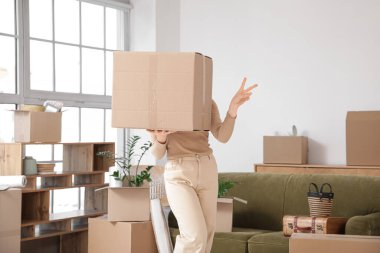 Taşındığı gün odada karton kutu taşıyan genç bir kadın.