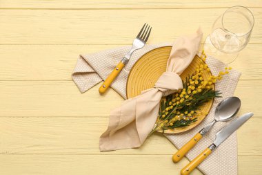 Sarı ahşap arka planda mimoza çiçekleri olan güzel bir masa.