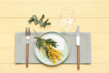 Mimoza çiçekleri ve sarı ahşap arka planda okaliptüs olan güzel bir masa.