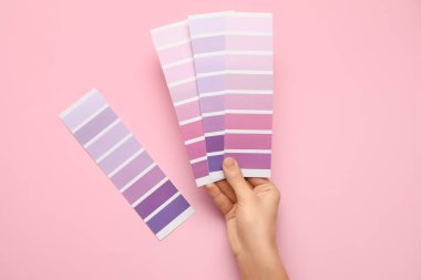 Pembe arka planda mor palet örnekleri olan kadın elleri. Üst görünüm