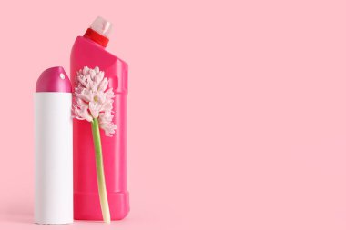Pembe arka planda bahar çiçeğiyle temizlik malzemeleri.
