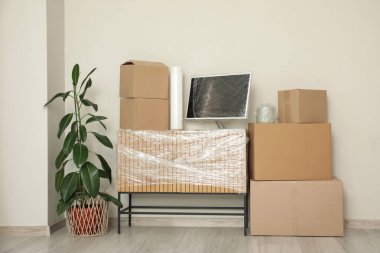 Çekmecelerin üzerine gerilmiş film sarılı bilgisayar monitörü ve odadaki kutuları taşıma