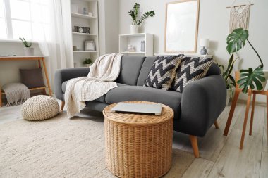 Oturma odasının içinde kanepe, sepet ve raf üniteleri var.