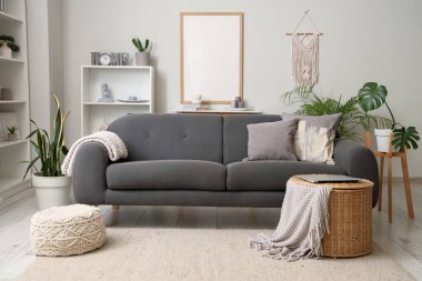 Oturma odasının içinde kanepe, boş çerçeve ve bitkiler var.