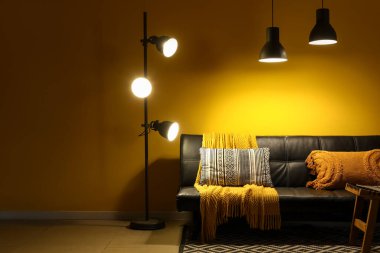 Modern siyah kanepesi, sehpası ve geceleri parlayan lambaları olan şık bir oturma odası.