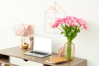 Masada güzel lale çiçekleri, dizüstü bilgisayarı ve kırtasiyesi olan modern işyerinin içi.