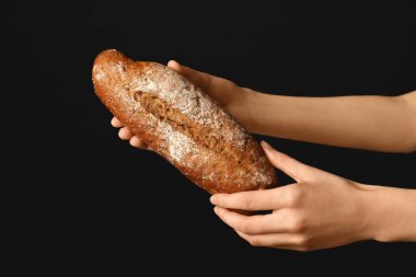 Siyah arka planda taze çavdar ekmeği olan kadın elleri.