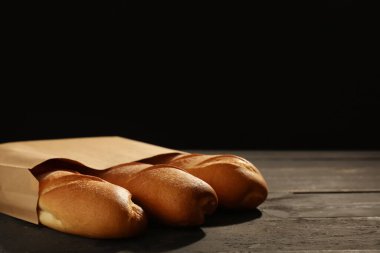 Siyah ahşap masada taze baget torbası.