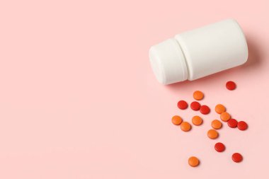 Pembe arka planda farklı haplar içeren kavanoz, yakın plan.