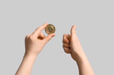 Bitcoin 'i olan kadın eller ışık arka planında başparmağını kaldırıyor