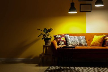 Kırmızı kanepesi, masası ve parlak lambaları olan karanlık oturma odasının içinde.