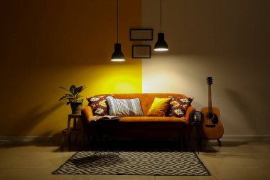 Kanepesi, gitarı ve parlak lambaları olan karanlık oturma odasının içinde.