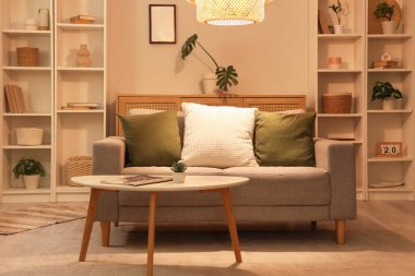 Gri kanepesi, kahve masası ve gece lambasıyla şık bir oturma odası.