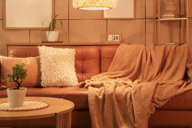 Kahverengi kanepesi, sehpası ve parlayan lambası olan şık bir oturma odası.