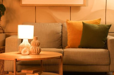 Gri kanepesi, kahve masası ve gece lambasıyla şık bir oturma odası.