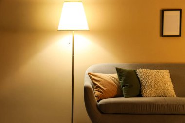 Gri kanepeli ve gece parıldayan standart lambalı şık bir oturma odası.