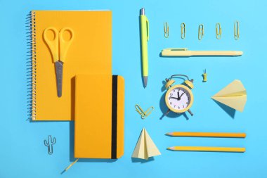 Saat, kağıt uçaklar ve mavi arka planda okul kırtasiyesiyle kompozisyon