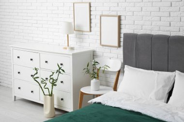 Şık yatak odasının içinde rahat bir yatak, şifonyer ve sandalyede bambu sapları.