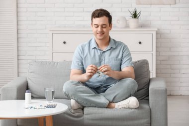 Evdeki kanepede oturan haplı genç adam.