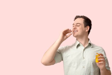 Mutlu genç adam pembe arka planda haplar alıyor.