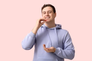 Mutlu genç adam pembe arka planda haplar alıyor.