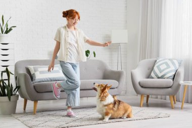 Evde Corgi köpeği olan kızıl saçlı genç bir kız.