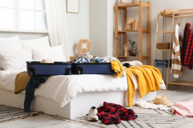 Dağınık giysilerle dolu bavulu dağınık yatak odasında aç